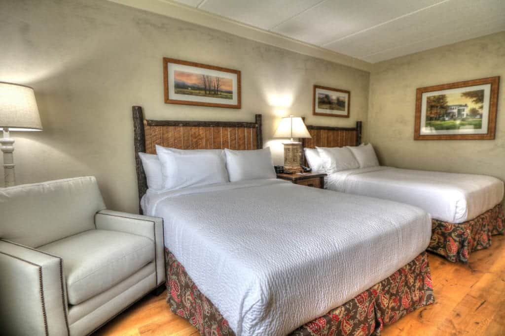 Room with two queen beds and comfy chair at The Lodge at Five Oaks hotel near Smoky Mountains